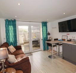 A living room with a sofa and kitchen area at The Old Dairy in Wadebridge