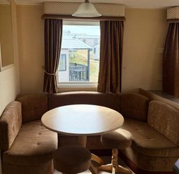 A dining area with a round table and seating at Haven Perransands, 575 Perranporth