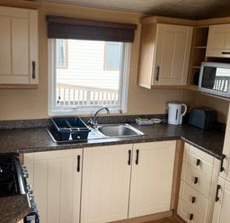 A kitchen with sink, stove, microwave, kettle, and toaster at Haven Perransands, 575, Perranporth