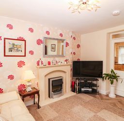 A living room with a television and sofa at Craig Y Glyn Cottage in Pwllheli