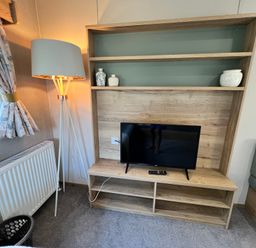 A living room with a television and lamp at Hafan y Mor - 159 Snowdonia Pwllheli