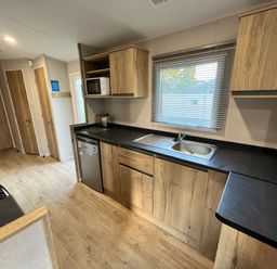 A kitchen with cabinets, sink, stove, and microwave at Hafan y Mor - 159 Snowdonia in Pwllheli