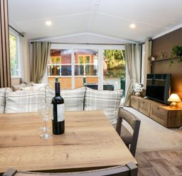 A living room with a dining table and wine bottle at Lake It Easy Troutbeck Bridge
