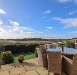 A garden with a table and chairs overlooking a field at Bay View in Weymouth