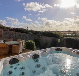 An outdoor area with a hot tub and dining table at Bay View in Weymouth