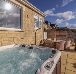 An outdoor area featuring a hot tub and dining table at Bay View in Weymouth