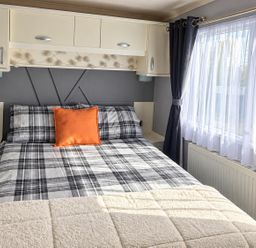 A bedroom with a bed and windows at 3 Bedroom Seafront Caravan, Sleeps 6 with Parking