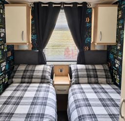 A bedroom with two single beds and gaming-themed wallpaper at 3 Bedroom Seafront Caravan, Sleeps 6 with Parking