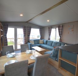 A living room with a sofa and dining area at Perran Sands Holiday Park - 615 Chy-an-Mor Perranporth