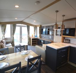 A living room with a dining area and kitchen at Perran Sands Holiday Park - 620 Chy An Mor in Perranporth