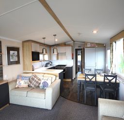 A living room with a sofa and dining area at Perran Sands Holiday Park - 620 Chy An Mor in Perranporth