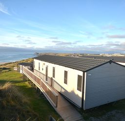 A caravan with decking overlooking the sea at Perran Sands Holiday Park - 621 Chy-an-Mor Perranporth