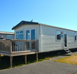 A mobile home with a deck and steps at Perran Sands Holiday Park - 725 Kernow View Perranporth
