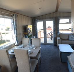 A living room with a dining area and sofa at Perran Sands Holiday Park - 725 Kernow View, Perranporth