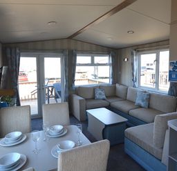 A living room with a sofa and dining table at Perran Sands Holiday Park - 725 Kernow View in Perranporth