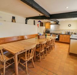 A kitchen with wooden dining table and chairs with kitchen appliances and black ceiling beams at Little Cowarne Court in Little Cowarne near Bromyard