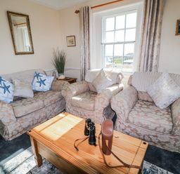A living room with sofas and a coffee table at Old Higher Lighthouse Stopes Cottage Portland Bill