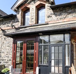 A stone building with two arched windows and wooden framed glass doors at 3 Railway Cottages in Betws-y-Coed