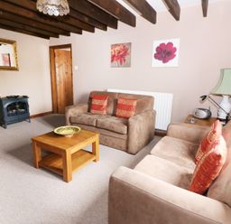 A living room with beige sofas and wooden coffee table at Cedar Cottage in Llanidloes