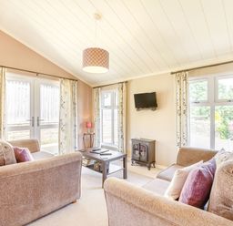 A living room with two sofas a coffee table a small stove and television at Lavender Lodge Charlton Horethorne near Sherborne