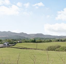 Green fields with sheep and stone fences and a few buildings with mountains in the background at 2 Bryn Tirion in Llan Ffestiniog