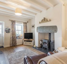 A living room with a wood stove fireplace a television and leather armchairs at 2 Bryn Tirion in Llan Ffestiniog