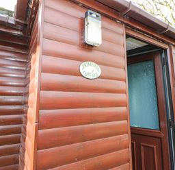 A wooden exterior wall with an outdoor light and a sign that reads primrose cottage at Primrose Lodge in Saltburn-by-the-Sea