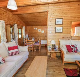 A living room with two sofas dining table bookshelf and wooden walls at Striding Edge White Cross Bay near Troutbeck Bridge