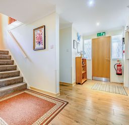 An entrance area with wooden floor a staircase a wooden door a fire extinguisher and wooden furniture at Eden House in Bardsea
