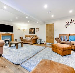 A living room with brown sofas a wooden coffee table and a wall mounted tv at Eden House in Bardsea