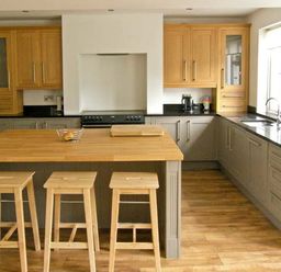 A kitchen with wooden stools at a wooden island and cabinets at Llechwedd in Dolgellau