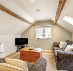 A living room with sofas a wooden coffee table and a television at Upstairs Downstairs Cottage in Snainton near Scarborough