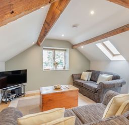 A living room with sofas a wooden coffee table a television and exposed wooden beams at Upstairs Downstairs Cottage in Snainton near Scarborough