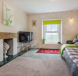 A living room with a television a sofa and a window with a green blind at Hillside Cottage in Peasedown St John near Bath