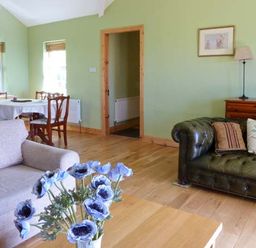 A living room with two sofas a table with blue flowers and a dining table with chairs at The Bay in Caherdaniel County Kerry