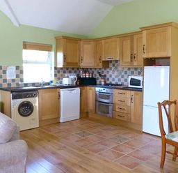 A kitchen with wooden cabinets appliances and dining chairs at The Bay in Caherdaniel County Kerry