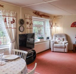 A living room with a sofa, dining table, and television at The Lodge in Old Buckenham near Attleborough