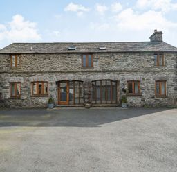 Stone cottage with multiple wooden windows and two large wooden doors with glass at Moresdale Bank Cottage in Lambrigg near Sedbergh and Kendal