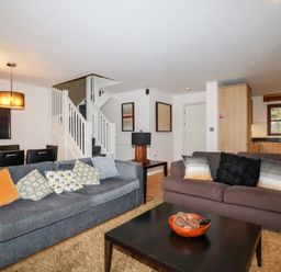 A living room with two sofas a coffee table and a dining area with chairs and lights at Lodge 22 Cherry in Wadebridge