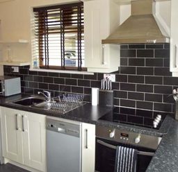 A kitchen with a washing machine dishwasher oven sink microwave and utensils at Hartam House in Falstone near Kielder and Bellingham