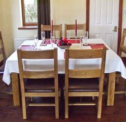 A dining room with a rectangular table set with six wooden chairs at Hartam House in Falstone near Kielder and Bellingham