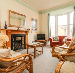 A living room with a fireplace chairs a sofa a coffee table and a television at Penryn in Ilfracombe