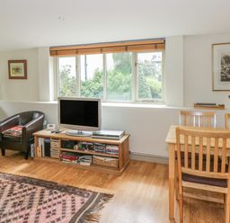 A living room with two leather chairs a TV on a wooden stand and a dining table with chairs at Pembridge Cottage in Welsh Newton