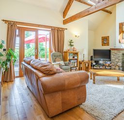 A living room with leather sofas wooden coffee table and a television near a stone fireplace at Ysgubor Hir in Pontarddulais near Swansea
