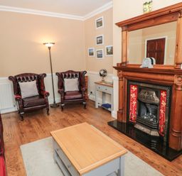 A living room with leather armchairs a wooden fireplace and a coffee table at Coquet Cottage in Amble