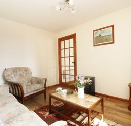 A living room with armchairs a coffee table with flower vase a television and a framed picture on the wall at The Old Granary in Polyphant near Launceston