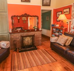 A living room with sofas pillows a rug a fireplace a mirror a bookshelf and a lamp at Kates Cottage in Knightstown Valentia Island County Kerry