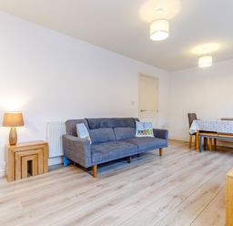 A living room with a blue sofa and wooden table with a lamp at Sunrise The Bay near Filey