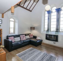 A living room with a sofa and a window at Eglwys St Cynfil in Penrhos near Pwllheli