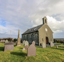 A church with gravestones in the foreground at Eglwys St Cynfil in Penrhos near Pwllheli